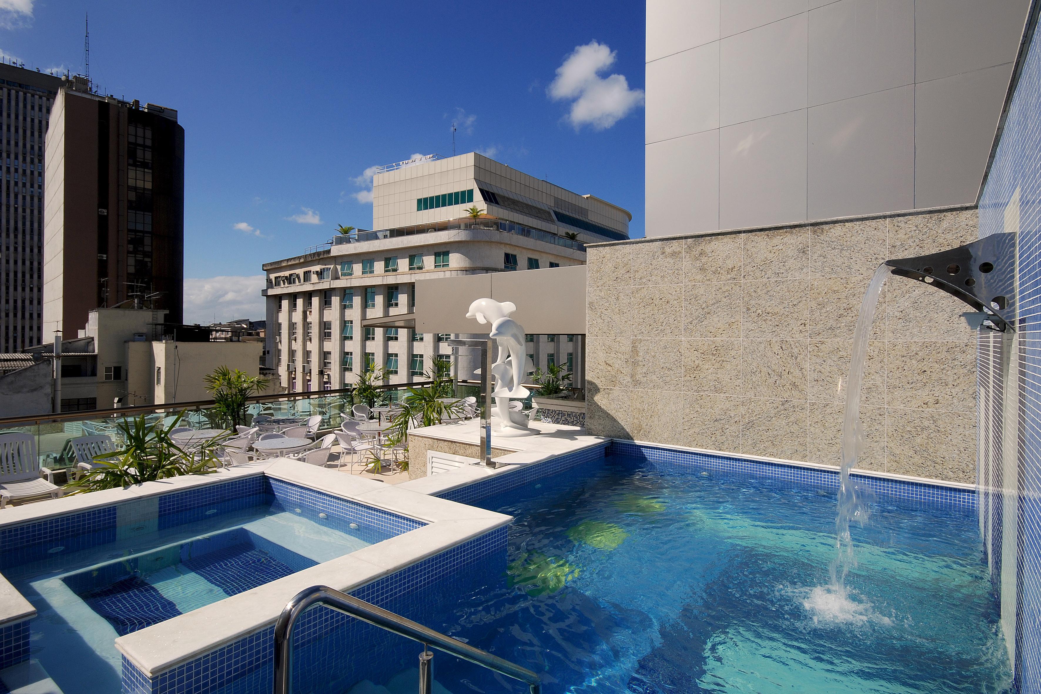 Hotel Atlantico Business Centro Rio de Janeiro Luaran gambar The photo shows a rooftop area featuring a swimming pool and a spa. The pool is inviting with a clear blue water, and there appears to be a waterfall feature. Surrounding the pool are areas for relaxation, possibly with sun loungers. In the backgroun